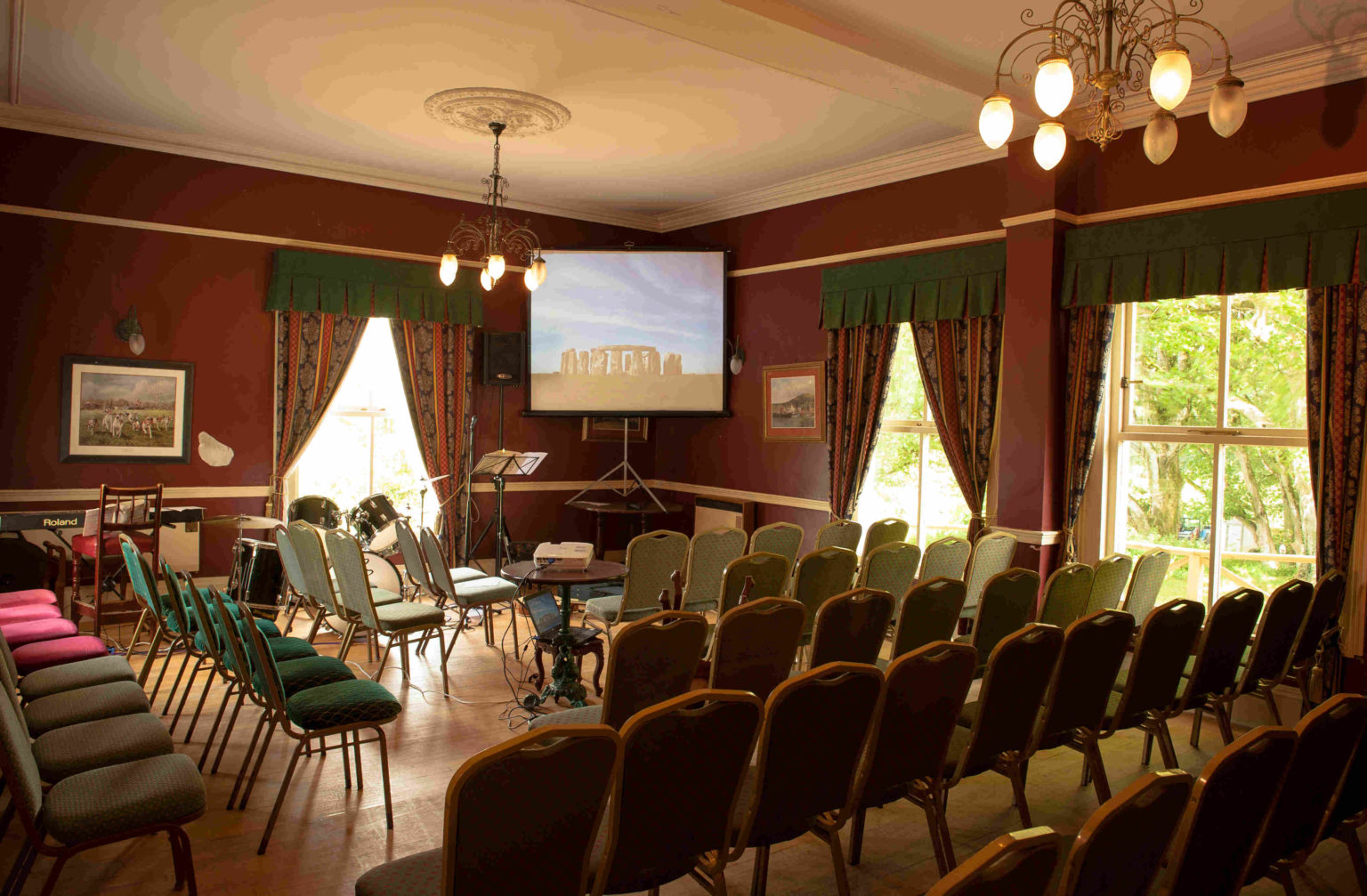 The meeting room set out with rows of chairs, a piano and a projector screen.
